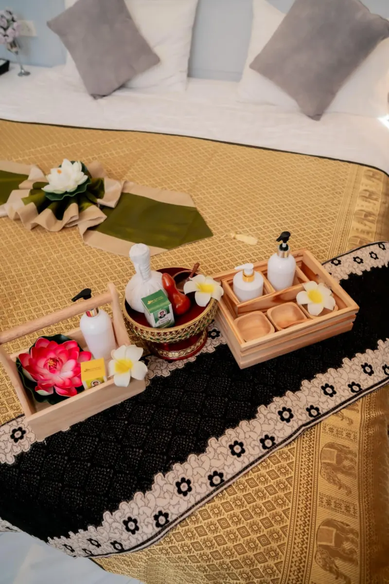 Thai massage set-up with herbal compress, oils and lotus flowers on a gold Thai-pattern cloth